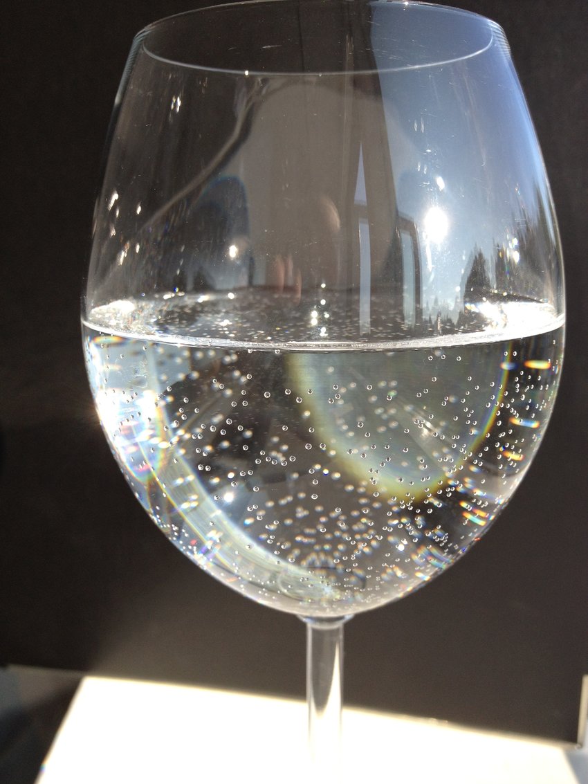 Glas gevuld met koud leidingwater (dat oververzadigd is) na 24 uur bij kamertemperatuur: Veel luchtbellen aan het oppervlak zijn gekerned en hebben het overleefd.